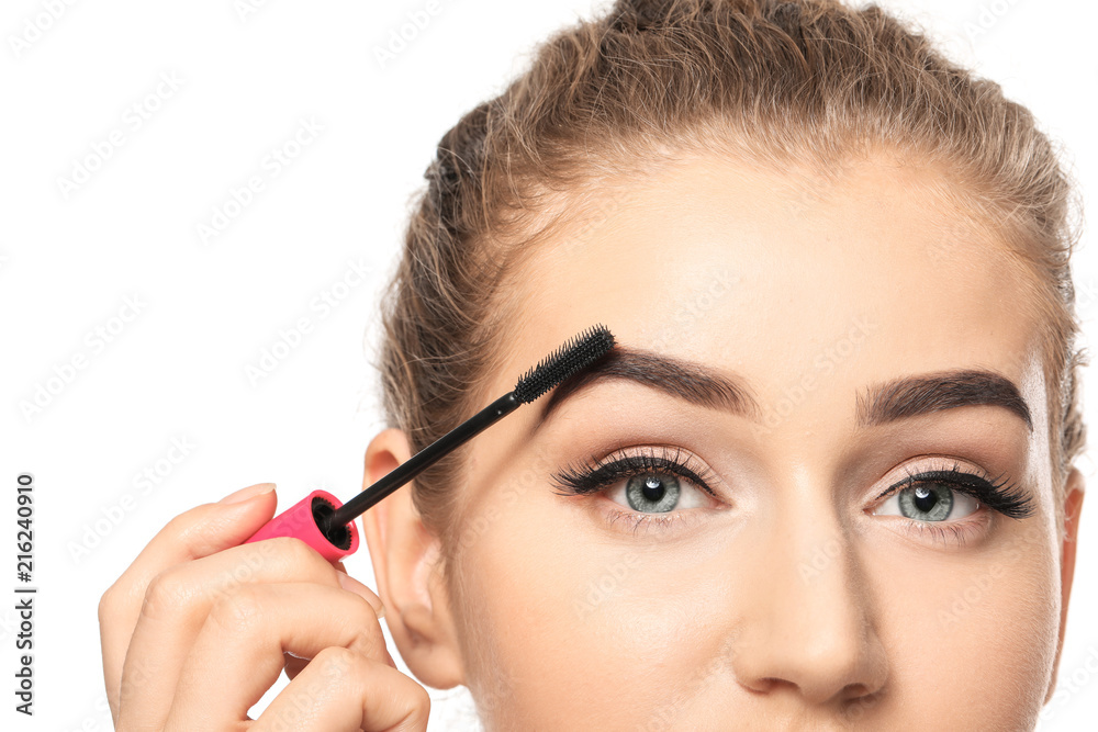 Young woman correcting shape of eyebrows on white background, closeup