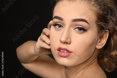 Young woman with beautiful eyebrows on dark background, closeup