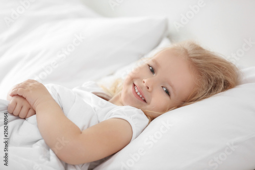 Little girl lying on white pillow at home
