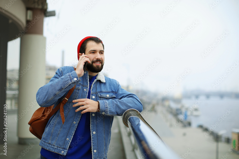 Handsome trendy hipster talking on mobile phone outdoors
