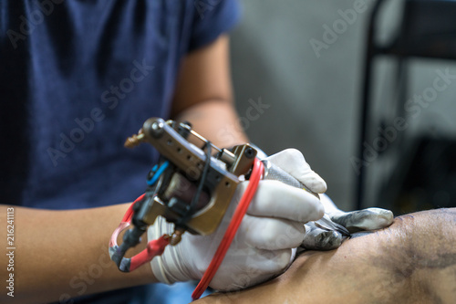 Tattoo artist in white gloves making a tattoo on man arm