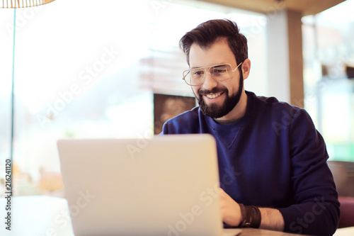 Handsome trendy hipster using laptop in cafe