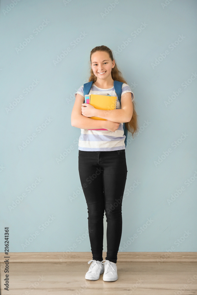 Teenage girl with backpack and notebooks on color wall background Teenage girl with backpack and notebooks on color wall background