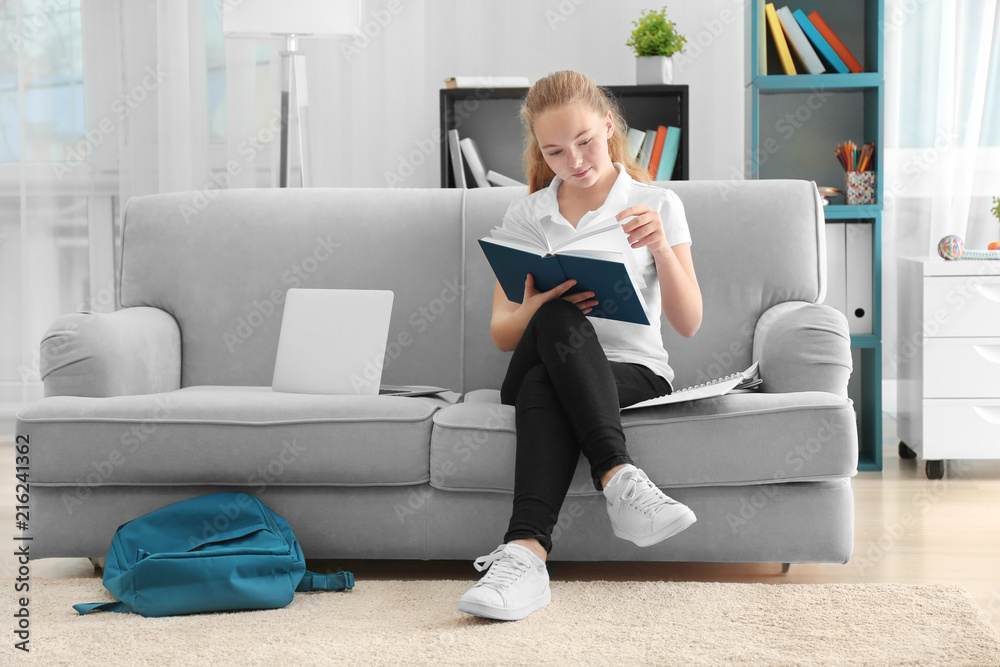 Teenage girl in school uniform reading book at home Teenage girl in school uniform reading book at home