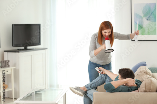 Angry woman with bills usin...