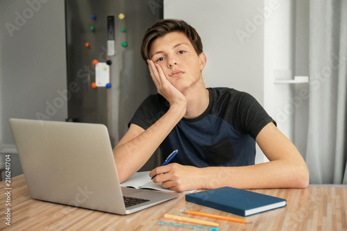 Tired teenager boy doing ho...