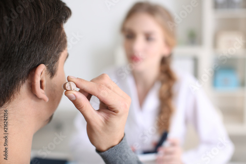 Man putting on hearing aid ...