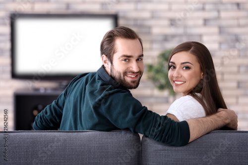 Young couple watching TV at...