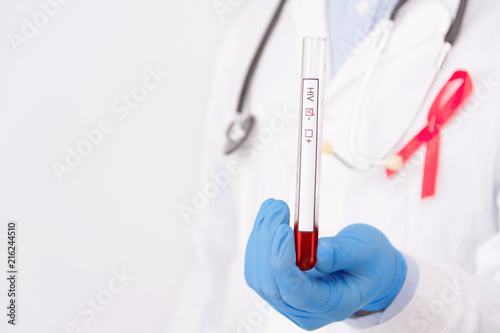 Safe sex healthcare concept. Doctor wearing white coat with pinned a red ribbon as symbol of hiv aids and stethoscope holding negative tumor marker / blood test. 