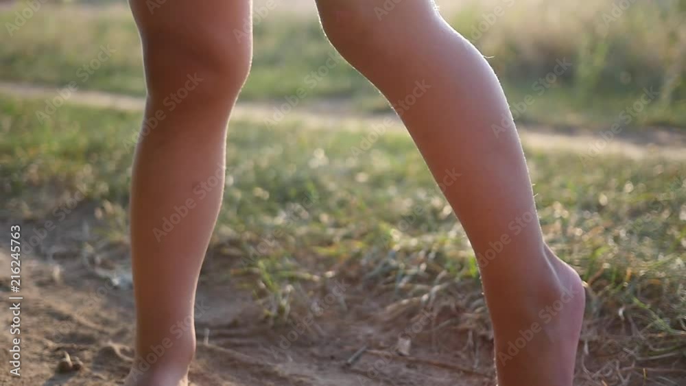 Cute little kid girl naked legs barefoot stay on a nature ground portrait posing