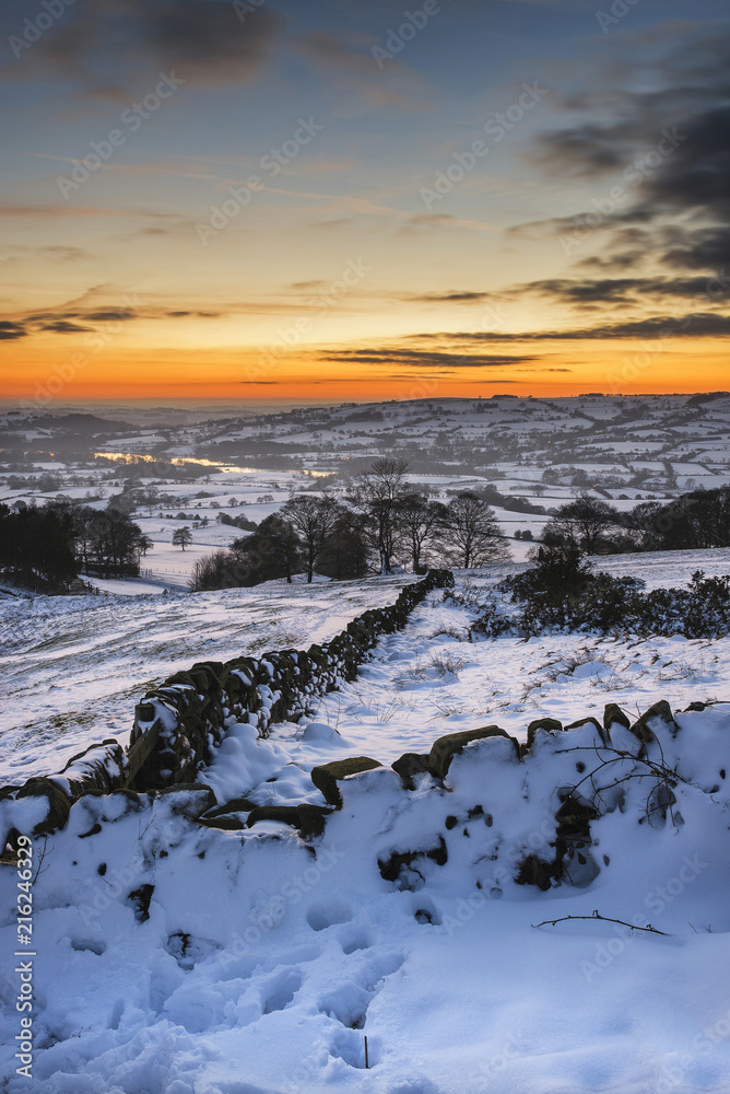 Stunning Winter sunset over snow covered Winter landscape in Peak District