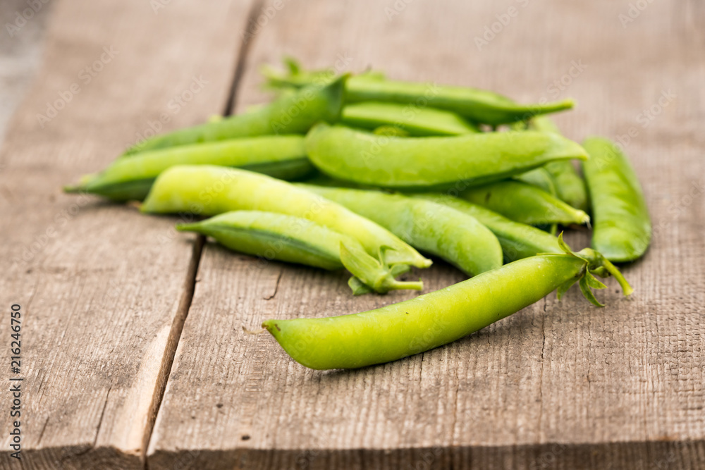 a scattering of fresh green peas pods from the garden on a wooden background a scattering of fresh green peas pods from the garden on a wooden background