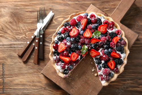 Delicious pie with ripe berries on wooden table, top view