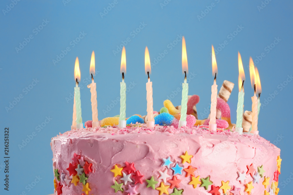 Tasty birthday cake with burning candles on color background, closeup Tasty birthday cake with burning candles on color background, closeup