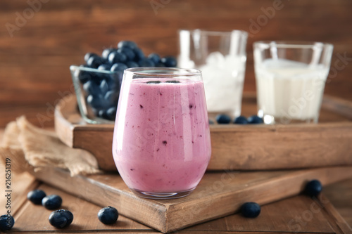 Glass of tasty blueberry smoothie on table