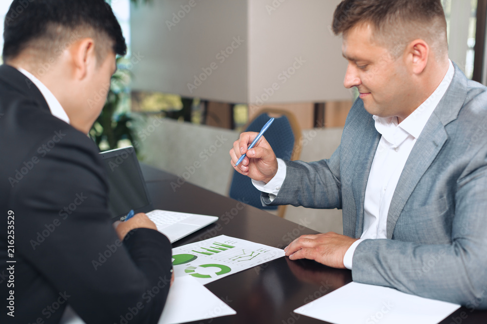 Fototapeta premium Portrait of two business partners sitting at a table together and working.