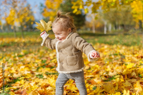 The cheerful little girl plays in the autumn park.