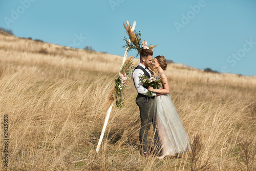 beautiful young couple man and woman standing in yellow field in summer