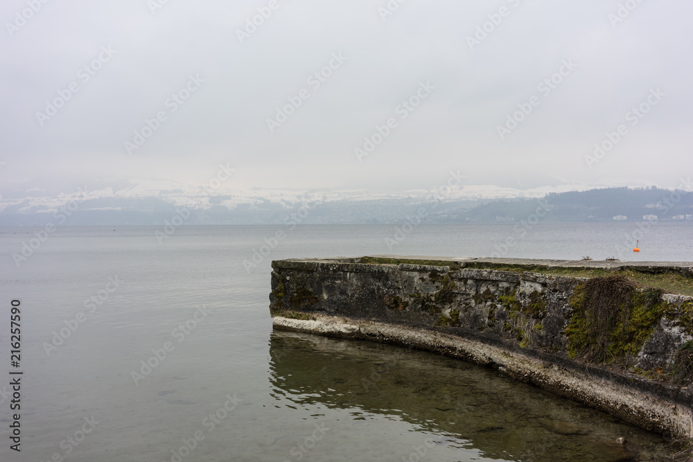 Obraz premium stone harbour at lake in winter with snow mountain landscape