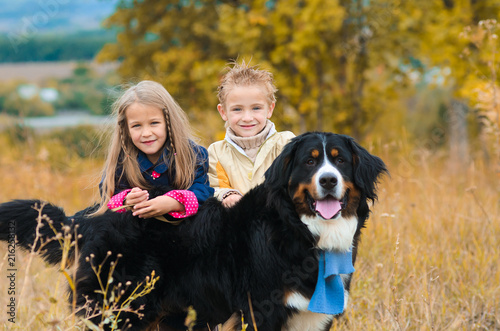 brother and his sister on walk with his four-footed dog friend on autumn meadow Berner Sennenhund © cheese78