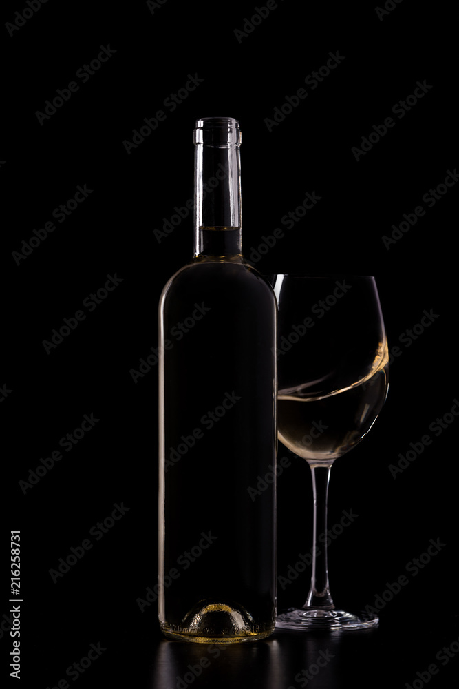Silhouette of white wine bottle with half glass isolated on black dark background with soft reflections and beautiful shadows. Studio shot. Silhouette of white wine bottle with half glass isolated on black dark background with soft reflections and beautiful shadows. Studio shot.