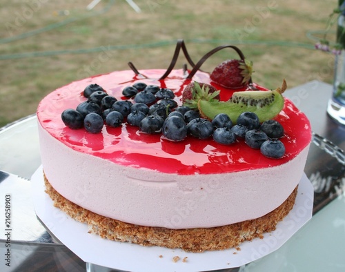 Cake with strawberry mousse, nut bottom, raspberry jellyy on top and decoration with blueberry , kiwi and strawberry