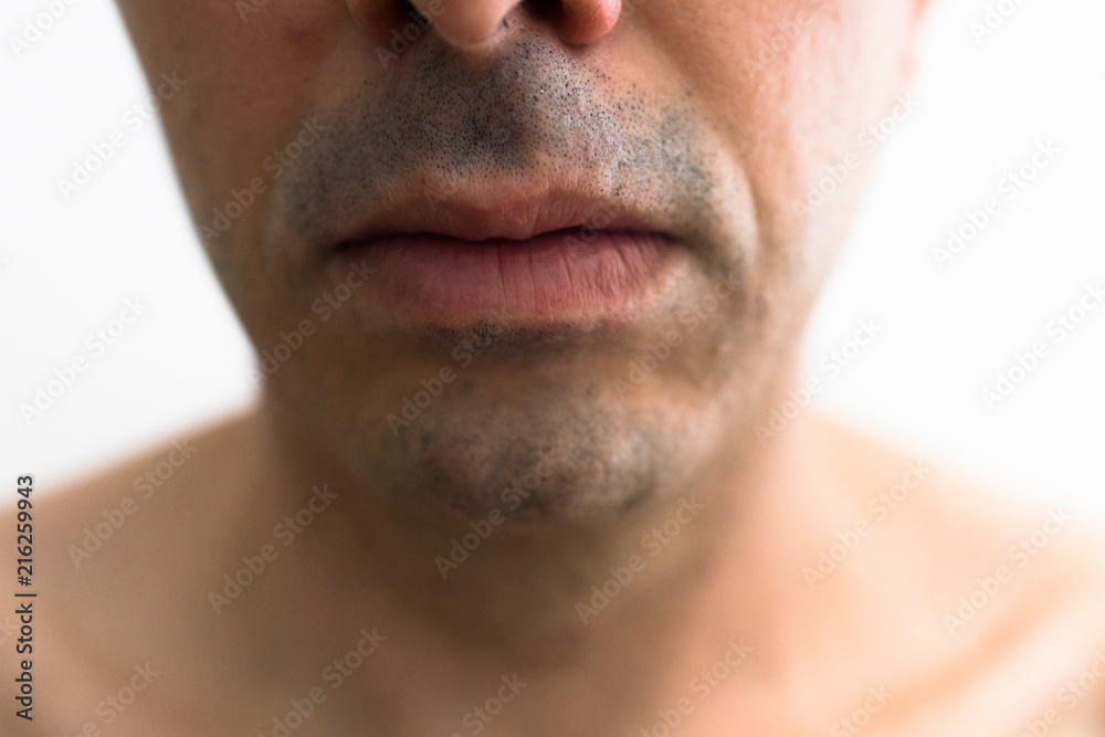 Fototapeta premium mouth of a man with a shaved beard. detail of the lips in the foreground with blurred white background. lower part of a white man's face