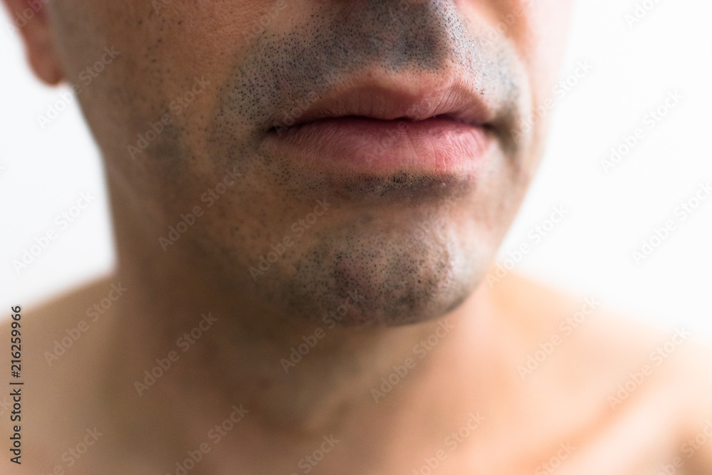 Obraz premium mouth of a man with a shaved beard. detail of the lips in the foreground with blurred white background. lower part of a white man's face