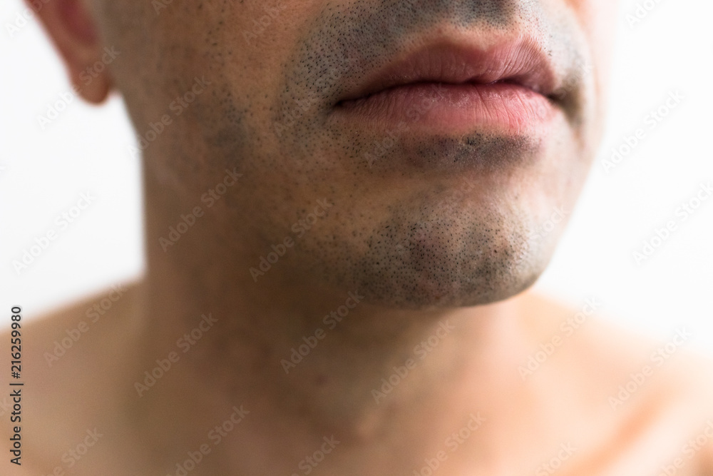 Obraz premium mouth of a man with a shaved beard. detail of the lips in the foreground with blurred white background. lower part of a white man's face