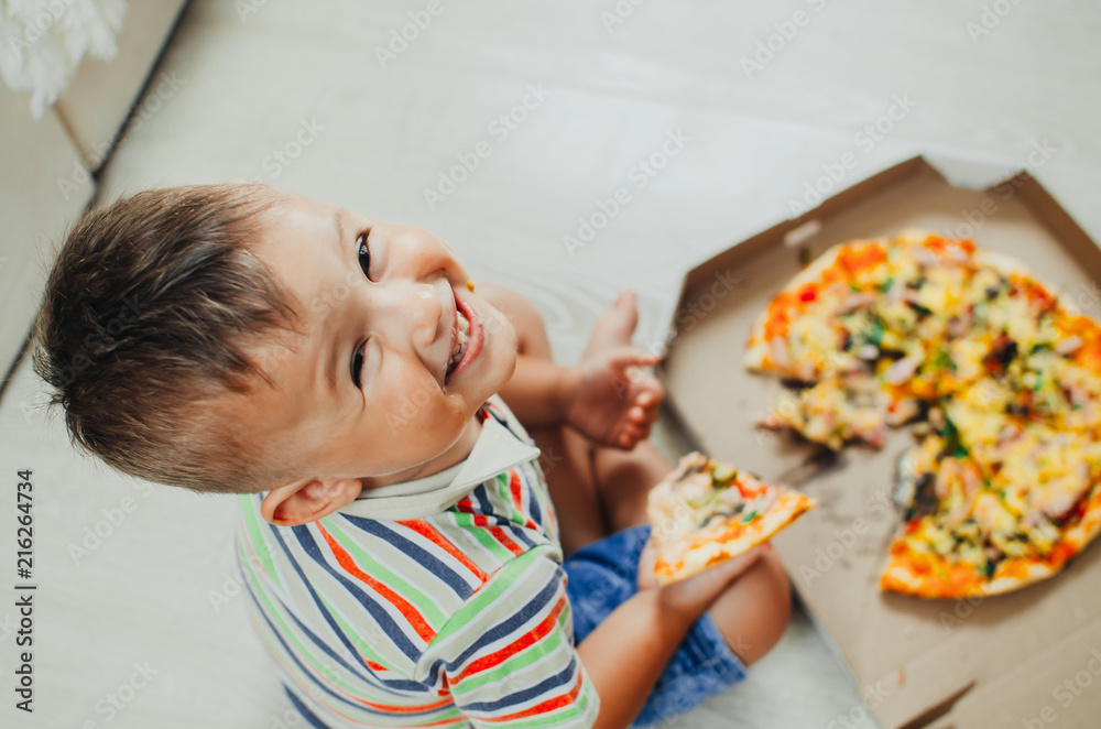 charming boy sitting on the floor eating pizza charming boy sitting on the floor eating pizza