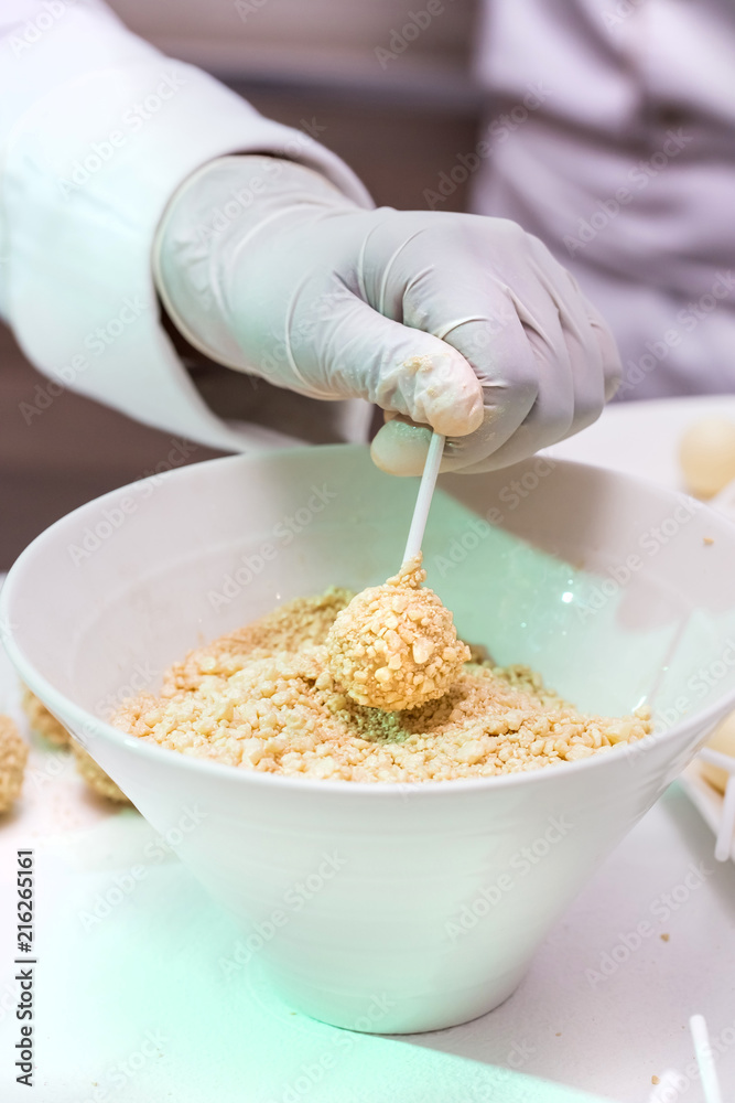 Chocolate lollipop being dipped into nuts in a bowl. Chocolate lollipop being dipped into nuts in a bowl.