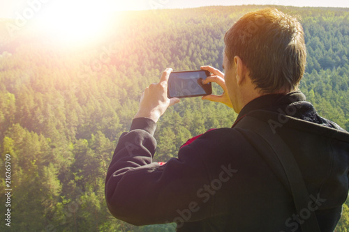Man tourist taking pictures on the phone nature, outdoors, against the sunset background