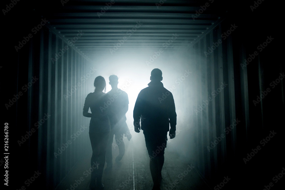 Light at the end of the tunnel. Silhouette of people in dark passage