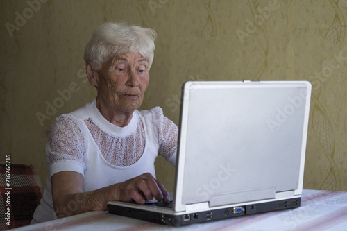 Portrait of smiling older woman working laptop computer indoors