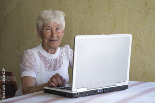 Portrait of smiling older woman working laptop computer indoors