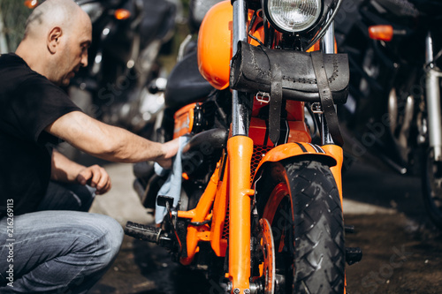 Adult and experienced biker cleaning and washing his motorcycle