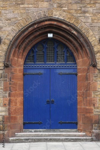 Painted blue arched door set in an ancient stone wall