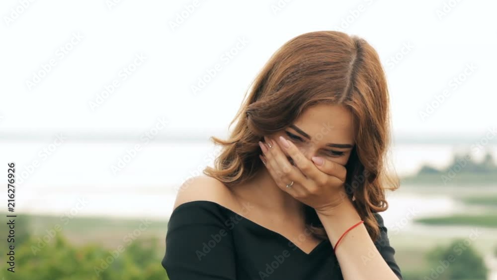 facial expressions of a young woman's face changes from a serious face and turns into sincere laughter, beautiful girl is walking in summer field facial expressions of a young woman's face changes from a serious face and turns into sincere laughter, beautiful girl is walking in summer field