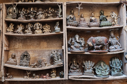 Many old statuettes on wooden shelves