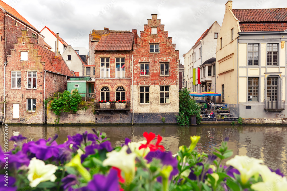 Nice view of picturesque medieval houses on the quay of Leie river and flowers, Old Town of Ghent, Belgium