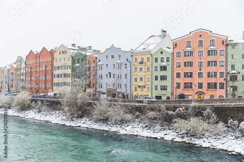 Austria, Innsbruck, row of colorful houses in winter with Inn River in the foreground