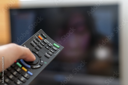 Remote control pointing towards the TV showing a woman just barely visible in the background