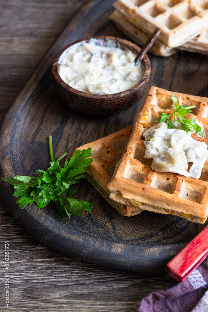 Savory waffles with corn and mushroom creamy sauce on a old wooden tray Savory waffles with corn and mushroom creamy sauce on a old wooden tray
