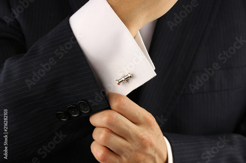 Elegant young fashion man fixing a gold cufflinks