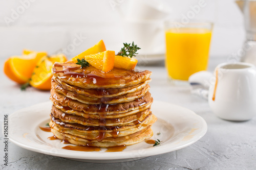 Table of breakfast . Pancakes with orange and sprinkled maple syrup, orange juice and coffee