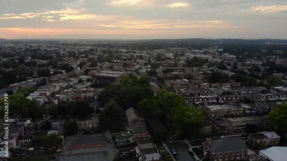 A slow aerial reverse flyover establishing shot of a Lancaster, Pennsylvania residential district at sunset on a hazy summer evening. A slow aerial reverse flyover establishing shot of a Lancaster, Pennsylvania residential district at sunset on a hazy summer evening.