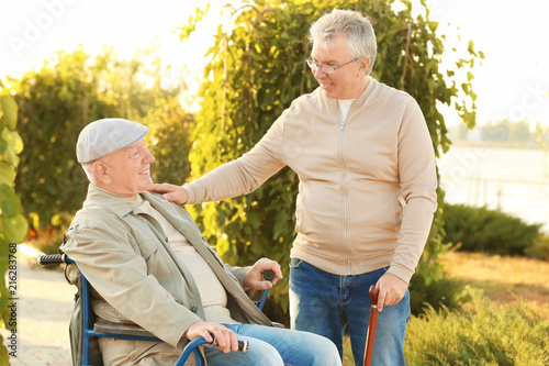 Senior man in wheelchair with his friend from care home outdoors © Africa Studio