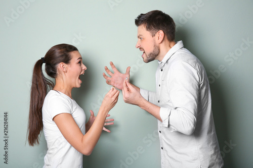 Young couple arguing on color background photo