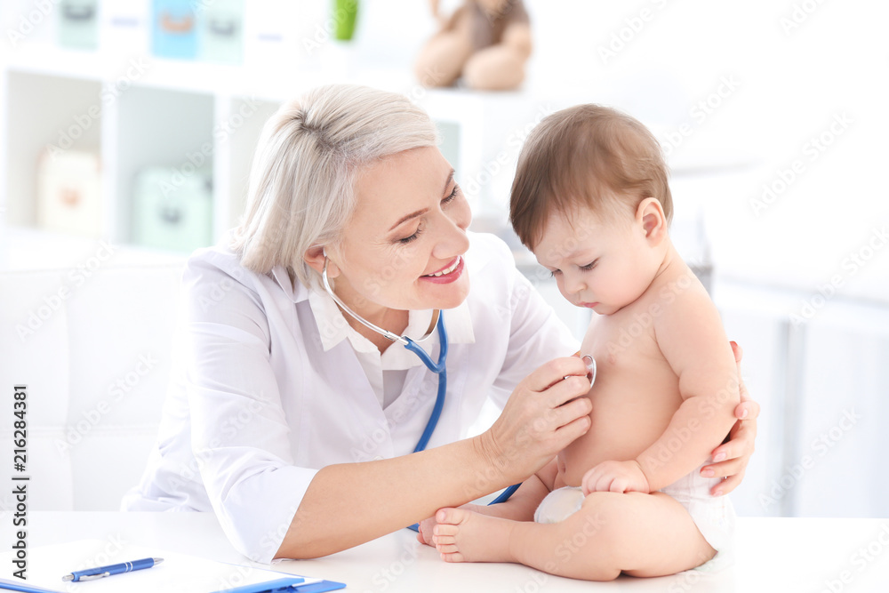 Mature female doctor examining baby boy in clinic Mature female doctor examining baby boy in clinic