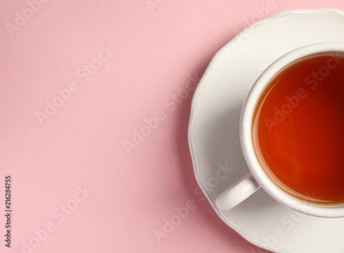 Cup of delicious tea with saucer on color background, top view